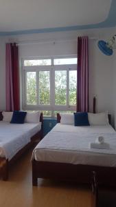 two beds in a room with two windows at Thanh Tran Guesthouse Lý Sơn in Ly Son