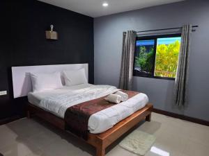 a bedroom with a bed with a teddy bear sitting on it at ใบตองรีสอร์ท in Ban Thung Kha Chomphu