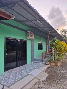 a green house with a door and a fan at ใบตองรีสอร์ท in Ban Thung Kha Chomphu