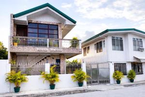 a white house with potted plants in front of it at PEPAYEN Homestay in General Luna