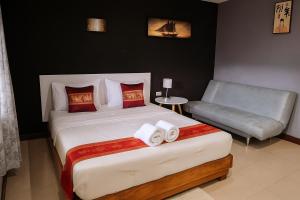 a bedroom with a large bed and a chair at ใบตองรีสอร์ท in Ban Thung Kha Chomphu