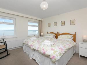 a bedroom with a large bed with a large window at Gosteg in Moelfre