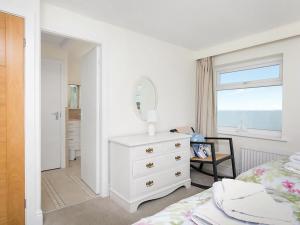 a bedroom with a bed and a dresser and a mirror at Gosteg in Moelfre +11 photos