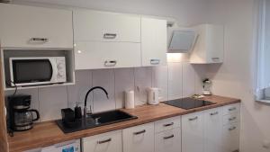 a kitchen with white cabinets and a sink and a microwave at Przestronny Apartament typu Studio, GARAŻ W CENIE in Wrocław
