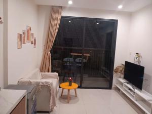 a living room with a television and a table in front of a window at GÂY THƯƠNG NHỚ Homestay Phòng trong vinhome grand park tên cũ I love vinhome grand park in Gò Công