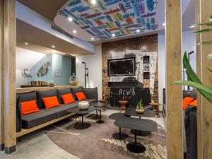 a living room with a couch and orange pillows at ibis Brignoles Provence Verte in Brignoles