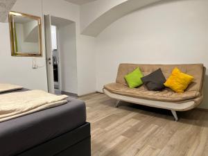 a couch with colorful pillows on it in a room at Brilliant Souterrain Apt - Prter Amuesement Park in Vienna +1 photo