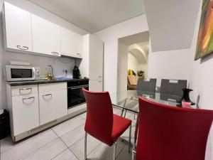 a kitchen with a glass table and red chairs at Brilliant Souterrain Apt - Prter Amuesement Park in Vienna
