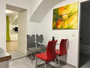 a dining room with red chairs and a painting on the wall at Brilliant Souterrain Apt - Prter Amuesement Park in Vienna