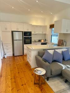 a living room with a couch and a kitchen at Botanical Gardens City Cottage in Geelong