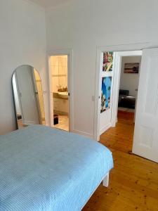 a bedroom with a blue bed and a mirror at Botanical Gardens City Cottage in Geelong