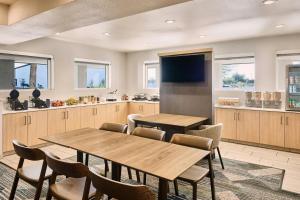 a kitchen with wooden tables and chairs and a television at SpringHill Suites Phoenix Glendale/Peoria in Peoria