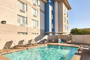 a swimming pool with chairs and a building at SpringHill Suites Phoenix Glendale/Peoria in Peoria