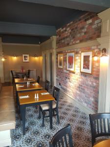 a restaurant with wooden tables and chairs and a brick wall at Cohannon Inn in Dungannon