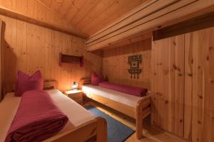 two beds in a room with wooden walls at Gasthof zur Traube in Pettneu am Arlberg