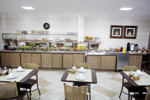 a restaurant with tables and chairs and a kitchen at Hotel Abib in Irati
