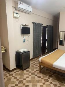 a bedroom with a bed and a tv and curtains at Hotel Beach Avenue in Calangute