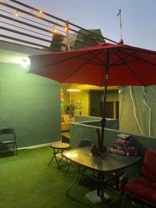 a patio with a table and a red umbrella at Departamento Mateo'S 505 in Ciudad Acuña