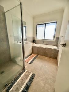 a bathroom with a shower and a tub and a window at Peaceful Room in Wyndham Vale for Stay in Wyndham Vale