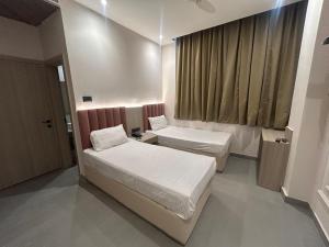 a small room with two beds and a window at Hotel Luxe in Kānpur