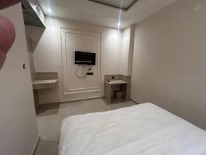a white bedroom with a bed and a tv at Hotel Luxe in Kānpur