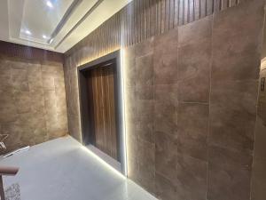 a bathroom with a tile wall with a door at Hotel Luxe in Kānpur
