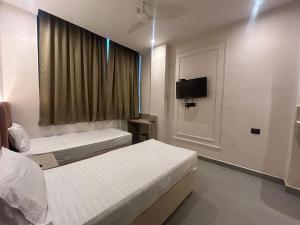 a hotel room with two beds and a television at Hotel Luxe in Kānpur +18 photos
