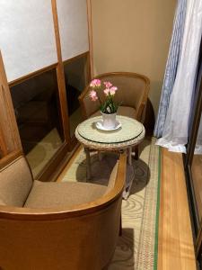 a table and chairs with a vase of flowers on it at 民泊ひなたぼっこ1日1組限定離れ貸切 in Nagano