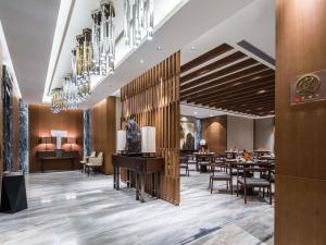 a restaurant with tables and chairs and a chandelier at 太原富力铂尔曼大酒店 in Taiyuan