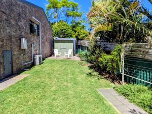 a backyard with a fence and a grass yard at Mollymook Den Coastal Retreat - Walk to Beach & Town in Mollymook +6 photos
