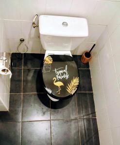 a toilet in a bathroom with a black and gold toilet seat at EVASION Bungalow Harmonie in Sarraméa