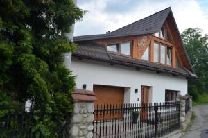 a white house with a black roof and a fence at House Apart 132 in Poronin