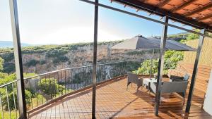 a balcony with a table and an umbrella at Το ΦΑΡΑΓΓΙ Του ΠΑΡΝΑΣΣΟΥ in Velítsa