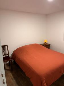 a bedroom with a orange bed and a chair at L'escapade in Bourg-en-Bresse