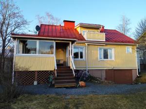 a yellow house with a red roof and two bikes at Villa Alice room 2 in Tampere
