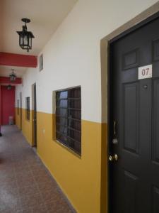an empty hallway with a black door and yellow and white walls at Rincón del Ángel in Villahermosa