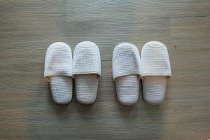 three pairs of white shoes on a wooden floor at A Plus Deluxe Hotel in Ko Lipe