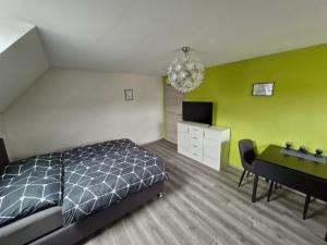 a bedroom with a bed and a desk and a television at Daniels Gästezimmer in Dockweiler