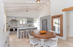 a kitchen with a wooden table and white chairs at Villa Moundela in Katsimátika