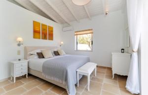 a white bedroom with a bed and a window at Villa Moundela in Katsimátika