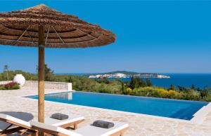 a pool with a straw umbrella and chairs and a swimming pool at Villa Moundela in Katsimátika