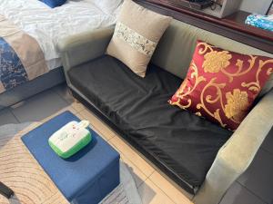 a couch with a pillow and a green foot stool at Lukang Hongyu Hostel in Lukang +5 photos
