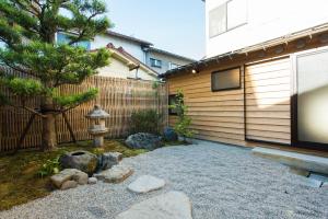 een achtertuin met een hek en een boom en een fontein bij Higashiyama Kageroi in Kanazawa