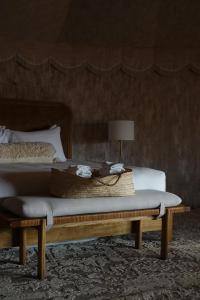 a bedroom with a bed and a bench with a table at Liwa Nights ليالي ليوا in Liwa