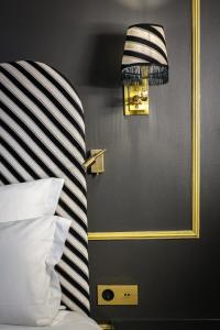 a bedroom with a bed with a striped headboard and a mirror at Snob Hotel in Paris