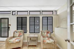 two chairs and a table in a room with windows at Beach Club Oasis #304 in Key West