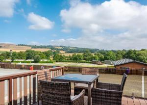 a patio with a table and chairs on a balcony at Rockbridge Country Park in Presteigne