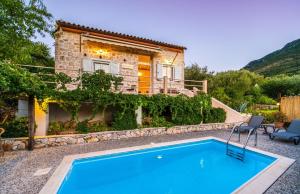 a house with a blue pool in front of it at Amalthia Cottage in Vathi