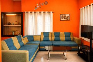 a living room with a blue couch and an orange wall at Varkala Days Home Stay in Varkala