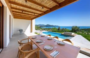 a dining room with a table and chairs and a swimming pool at Villa Anthilia in Syvota